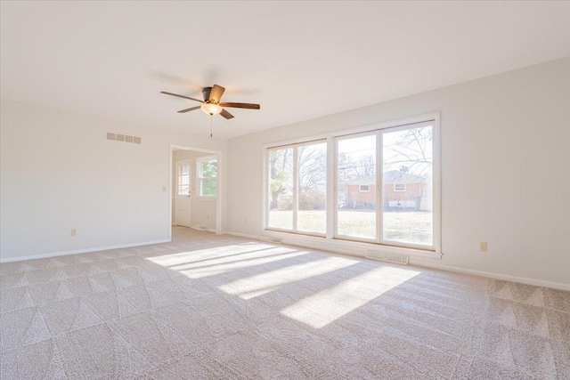 unfurnished room featuring light carpet, visible vents, baseboards, and ceiling fan