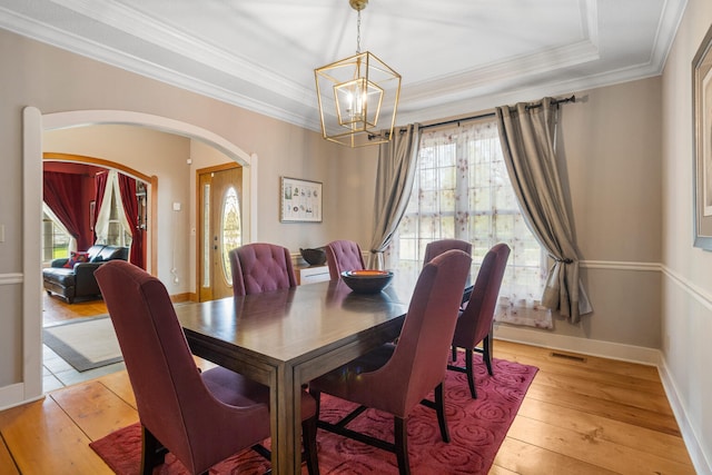 4201 Brittany Trail Dr, Champaign, IL 61822 - dining space featuring an inviting chandelier, visible vents, a raised ceiling, arched walkways, and light wood-style flooring