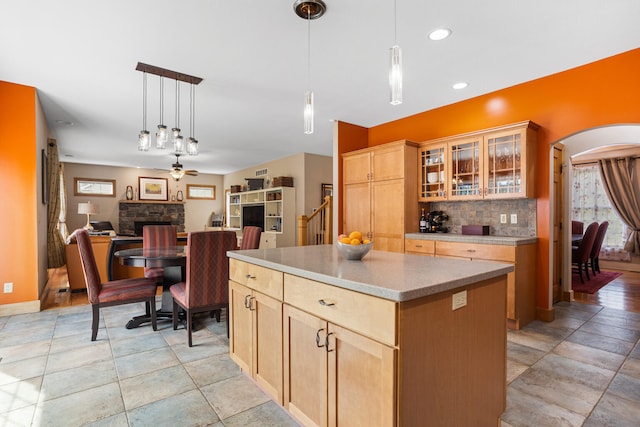 4201 Brittany Trail Dr, Champaign, IL 61822 - kitchen featuring decorative backsplash, a kitchen island, a ceiling fan, a stone fireplace, and arched walkways