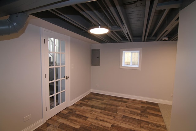 basement with dark wood-type flooring, electric panel, and baseboards