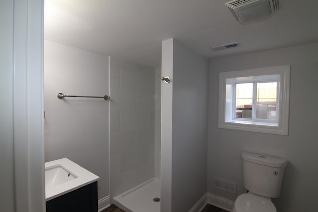 bathroom with toilet, visible vents, and a tile shower