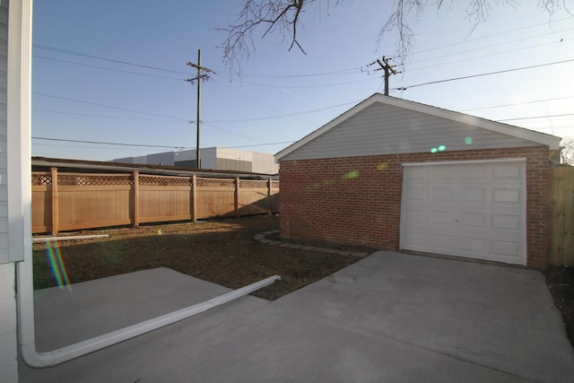 detached garage with concrete driveway and fence