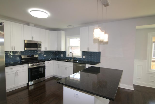 kitchen featuring dark wood-type flooring, a sink, backsplash, white cabinetry, and stainless steel appliances