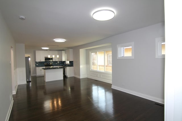 living room with a wainscoted wall, a decorative wall, visible vents, and dark wood-style flooring