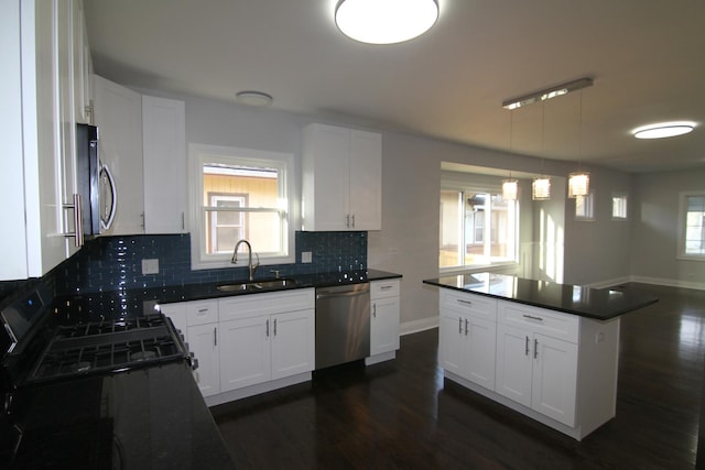 kitchen with dark countertops, dark wood-style floors, stainless steel appliances, and a sink