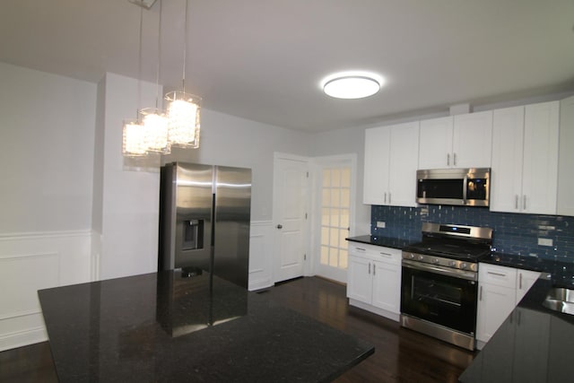 kitchen featuring dark wood-type flooring, stainless steel appliances, white cabinets, wainscoting, and decorative backsplash