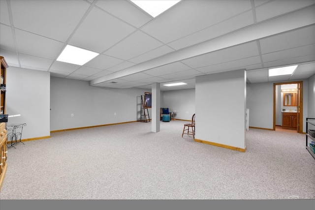 finished below grade area with carpet floors, baseboards, and a drop ceiling
