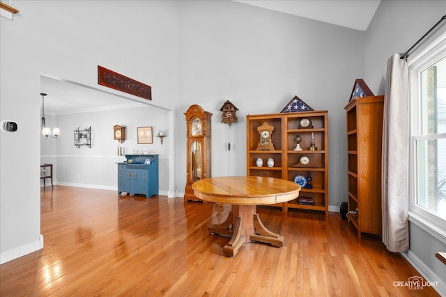 dining space with a chandelier, high vaulted ceiling, light wood-style flooring, and baseboards