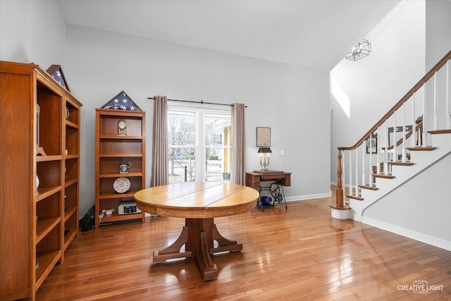 dining space with wood finished floors, baseboards, and stairway