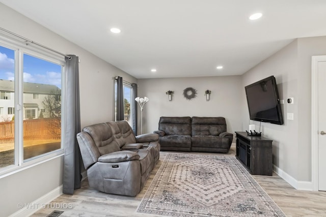 living area featuring recessed lighting, light wood-type flooring, baseboards, and a healthy amount of sunlight