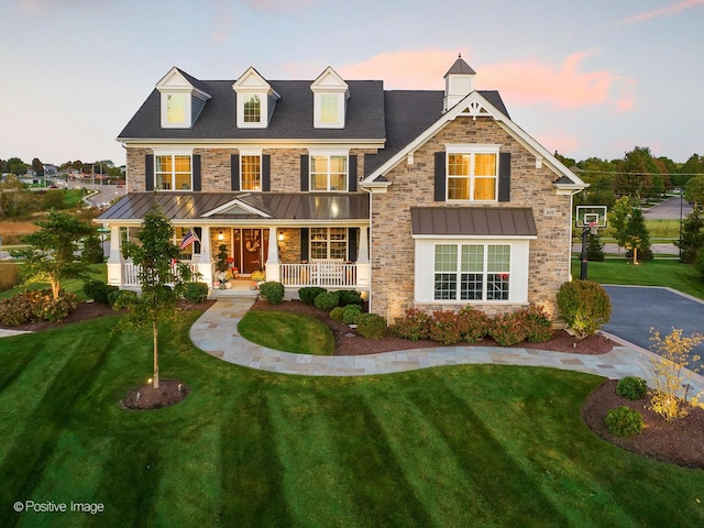 view of front of house with metal roof, a lawn, covered porch, and a standing seam roof