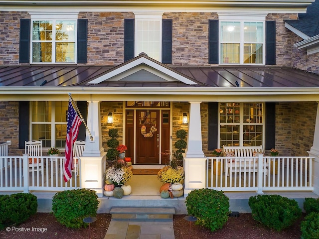 doorway to property featuring covered porch, metal roof, and a standing seam roof