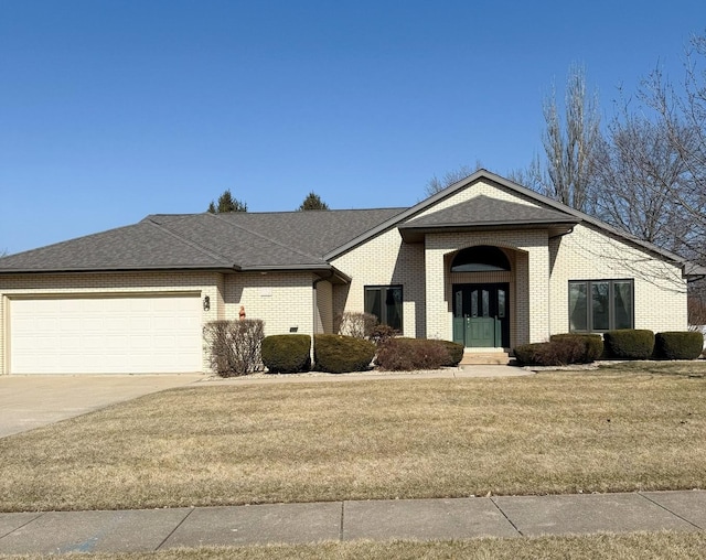 view of front of home featuring driveway, roof with shingles, an attached garage, a front lawn, and brick siding