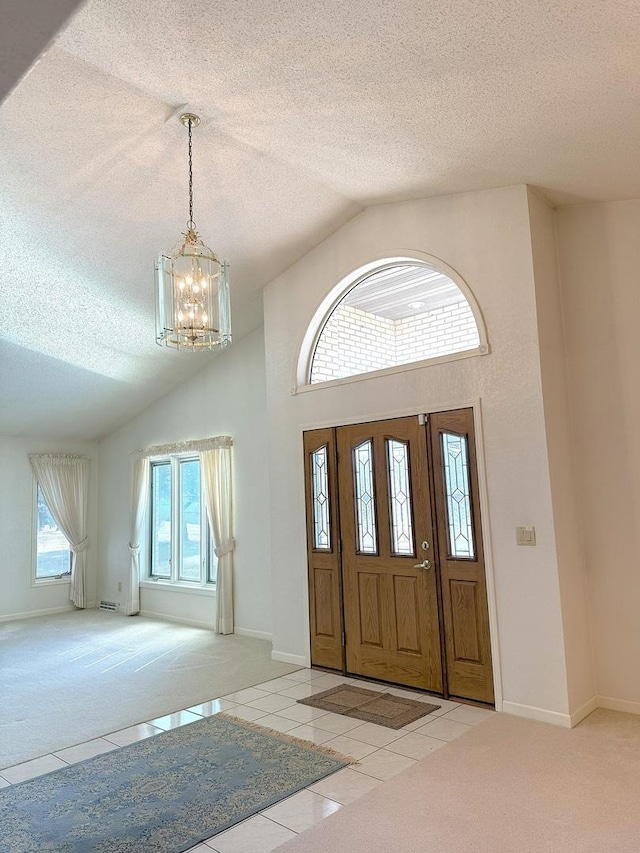 tiled foyer with an inviting chandelier, a textured ceiling, and carpet