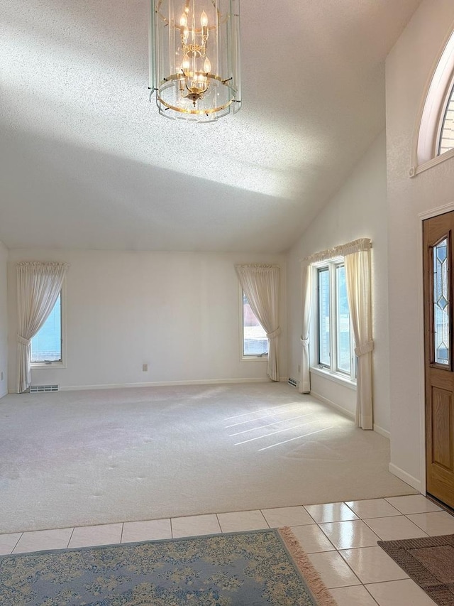 entryway featuring visible vents, a textured ceiling, an inviting chandelier, light tile patterned flooring, and light colored carpet