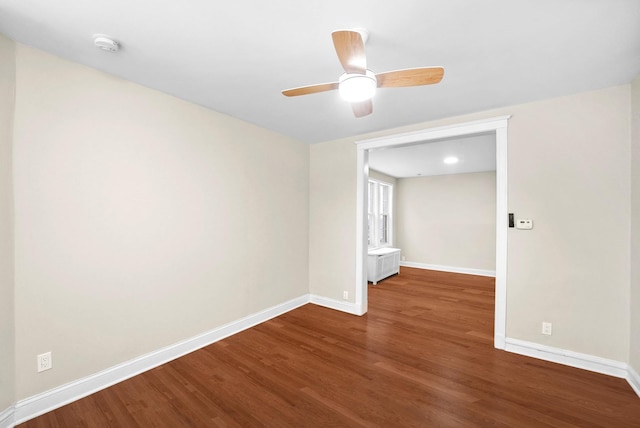 empty room with radiator, wood finished floors, and baseboards