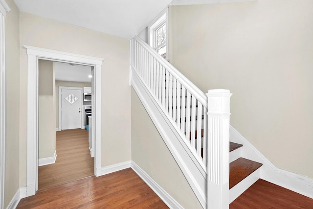 staircase with baseboards and wood finished floors