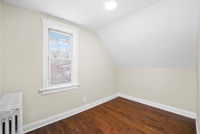 bonus room featuring dark wood-type flooring, radiator, baseboards, and vaulted ceiling