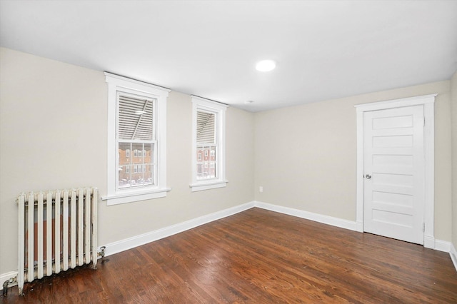 empty room featuring radiator heating unit, wood finished floors, and baseboards