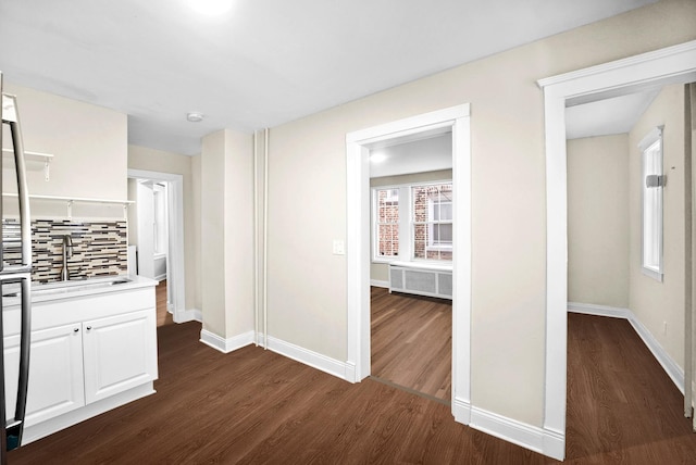 hall featuring radiator heating unit, baseboards, dark wood-style flooring, and a sink