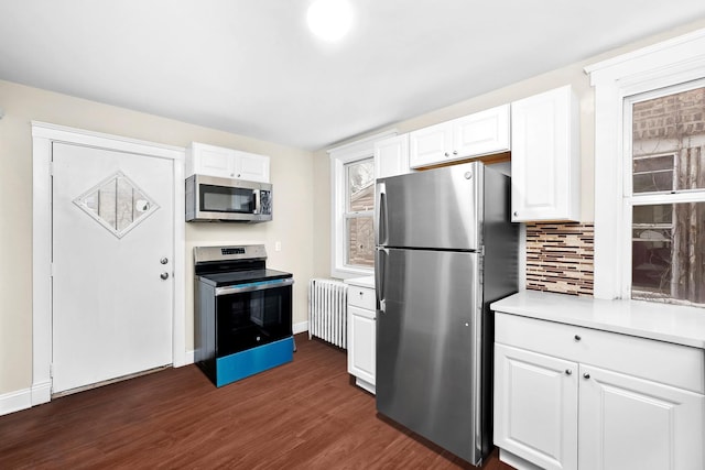 kitchen with tasteful backsplash, radiator heating unit, light countertops, stainless steel appliances, and dark wood-style flooring