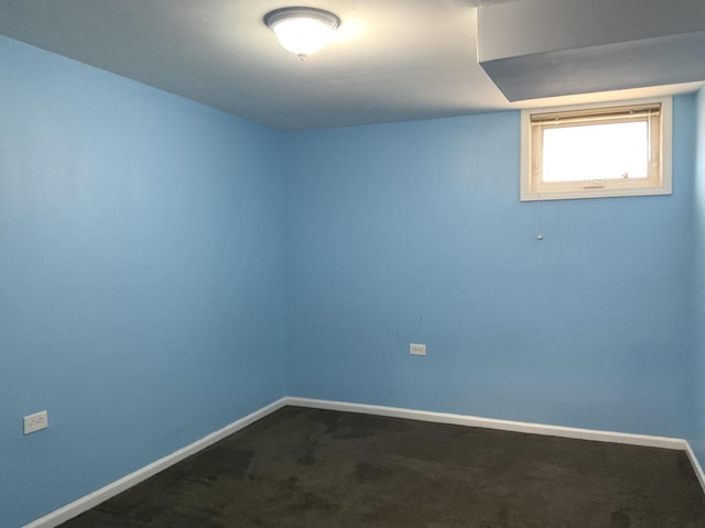 empty room with dark colored carpet and baseboards