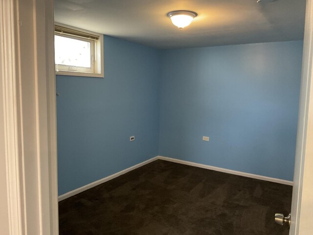 empty room with baseboards and dark colored carpet