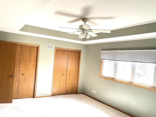 unfurnished bedroom with visible vents, ceiling fan, baseboards, and multiple closets