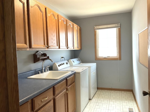 laundry area with visible vents, a sink, washer and dryer, cabinet space, and baseboards