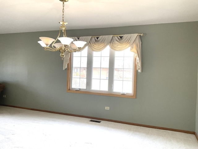 unfurnished room featuring an inviting chandelier, baseboards, and visible vents