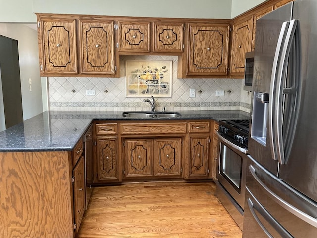 kitchen featuring a sink, stainless steel appliances, light wood-style floors, and brown cabinetry