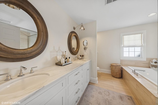 bathroom with a bath, double vanity, toilet, and a sink