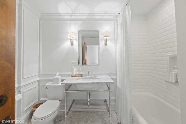 bathroom with toilet, shower / tub combo with curtain, ornamental molding, a decorative wall, and vanity