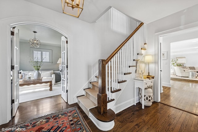 entrance foyer with hardwood / wood-style floors, an inviting chandelier, stairway, and arched walkways