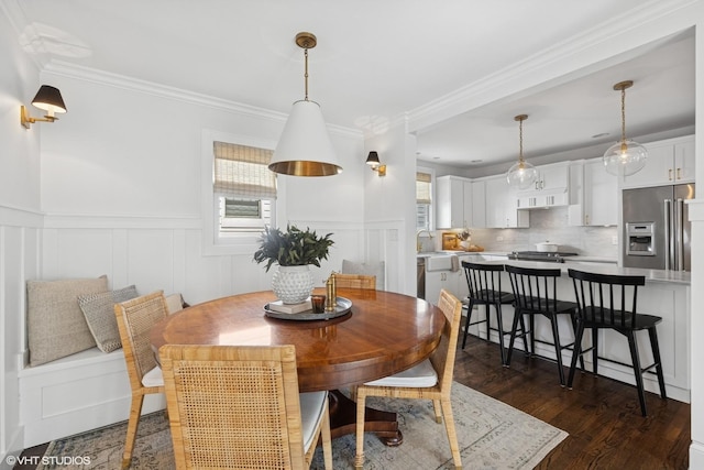 dining space featuring dark wood finished floors, wainscoting, and ornamental molding