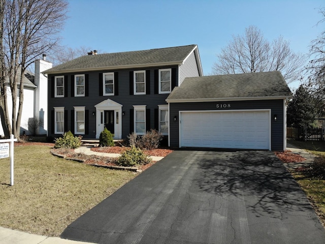 colonial house featuring a garage, a front yard, and driveway