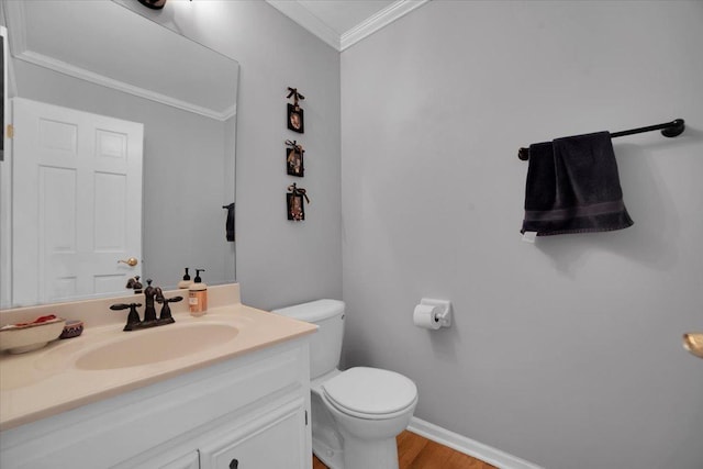 bathroom featuring vanity, wood finished floors, baseboards, crown molding, and toilet