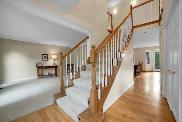 stairway with baseboards, a high ceiling, and wood finished floors