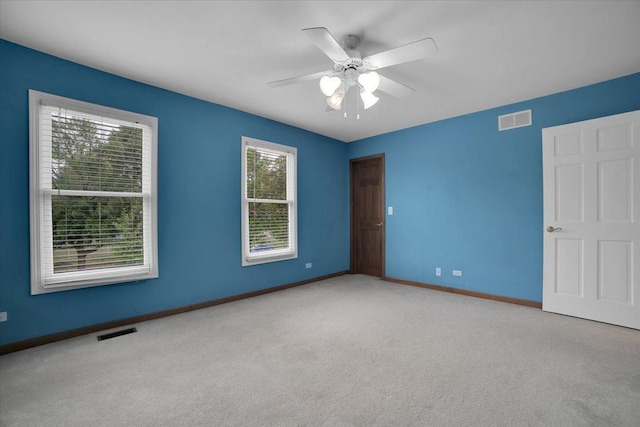 spare room featuring visible vents, carpet flooring, a ceiling fan, and baseboards