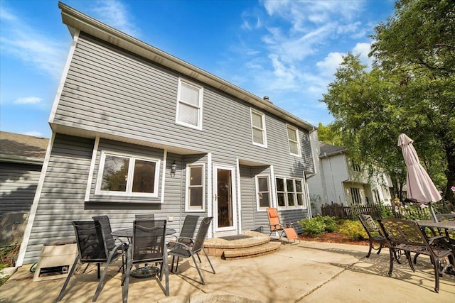 rear view of property with fence, outdoor dining space, and a patio area