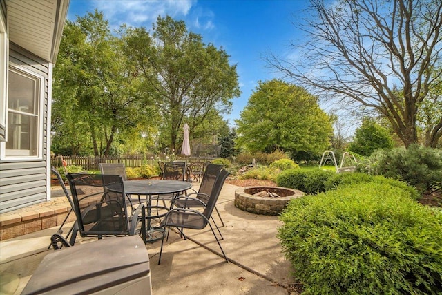 view of patio with outdoor dining space, a fire pit, and fence