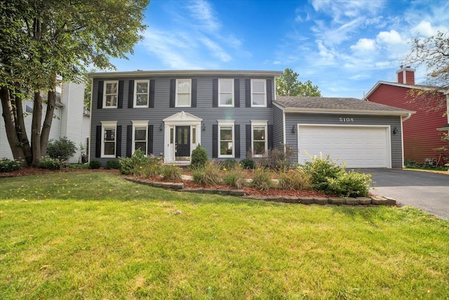 colonial house with a garage, a front yard, and driveway