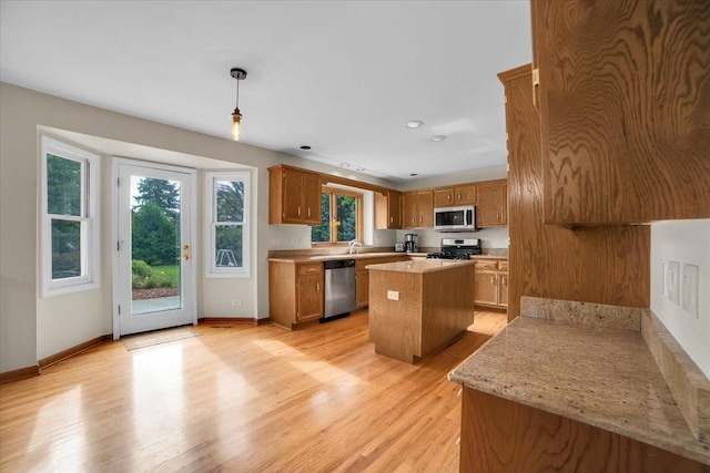 kitchen with a kitchen island, stainless steel appliances, light countertops, light wood-style floors, and brown cabinets