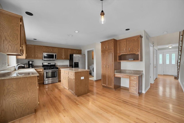 kitchen with a center island, light wood-style floors, appliances with stainless steel finishes, and a sink