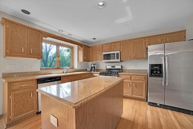 kitchen with light wood-style flooring, appliances with stainless steel finishes, a center island, and a sink