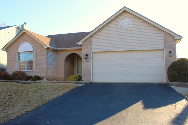 single story home featuring brick siding, driveway, a chimney, and a garage