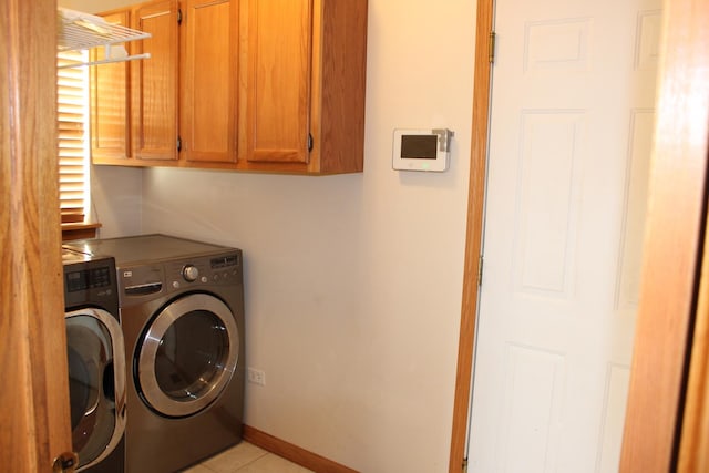 washroom featuring washer and dryer, light tile patterned floors, cabinet space, and baseboards