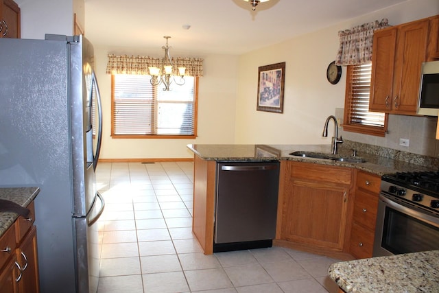 kitchen featuring tasteful backsplash, brown cabinets, a peninsula, stainless steel appliances, and a sink