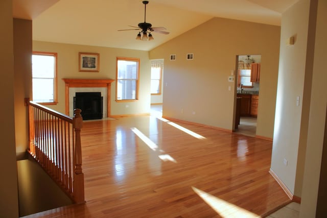 unfurnished living room featuring a fireplace with flush hearth, visible vents, lofted ceiling, and light wood-style floors