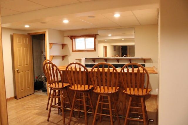 bar featuring baseboards, a drop ceiling, a dry bar, recessed lighting, and wood finished floors